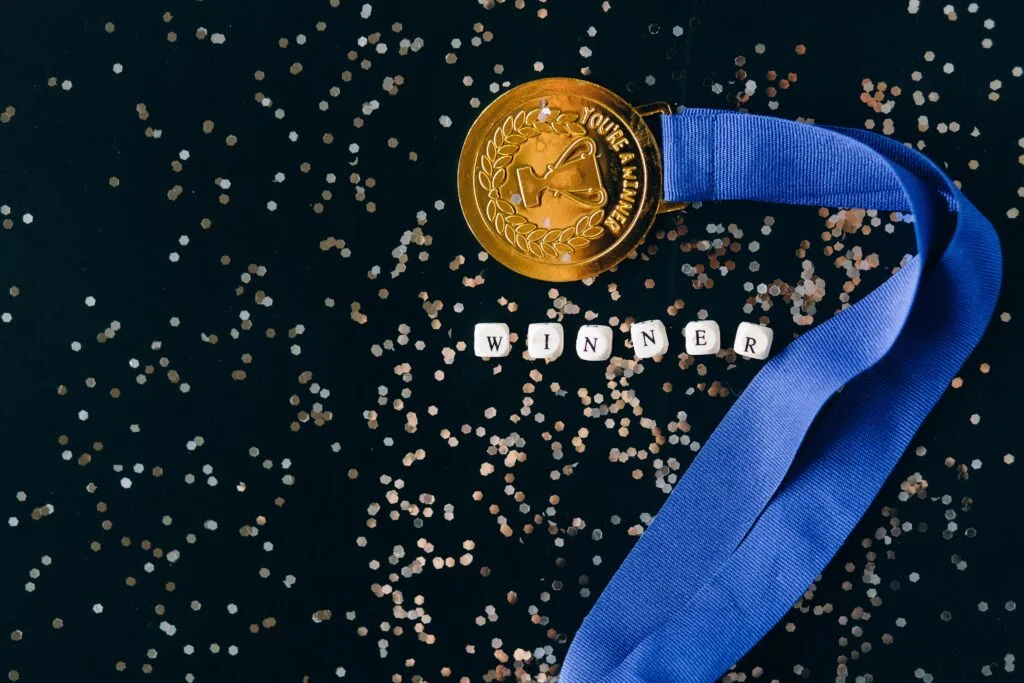 medalha de primeiro lugar com letras formando a palavra "winner" logo abaixo