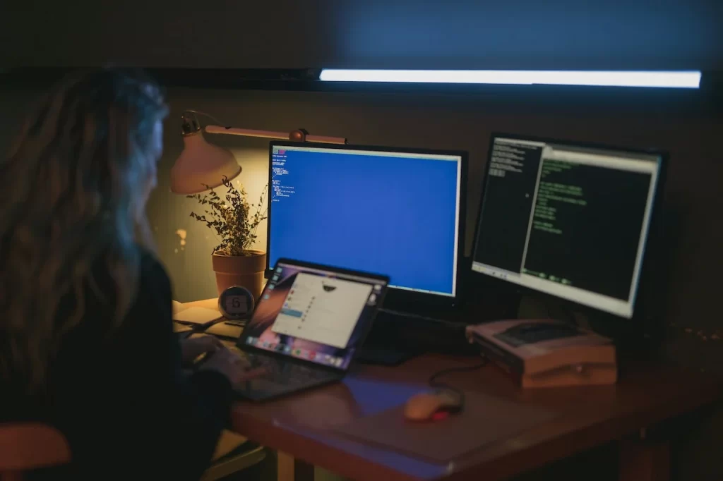 mulher sentada, mexendo em computadores num escritório