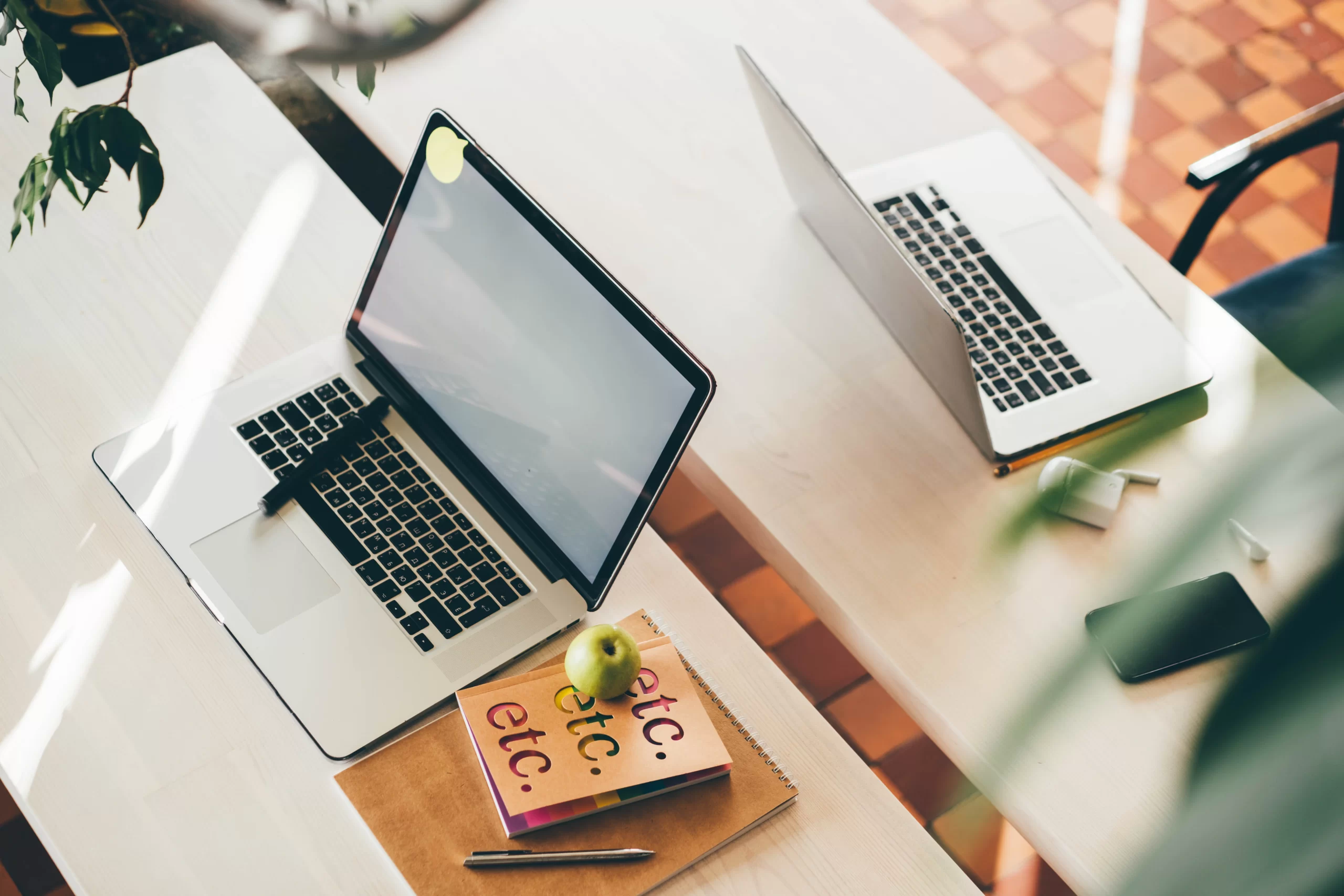 notebook acima de uma mesa num ambiente de coworking
