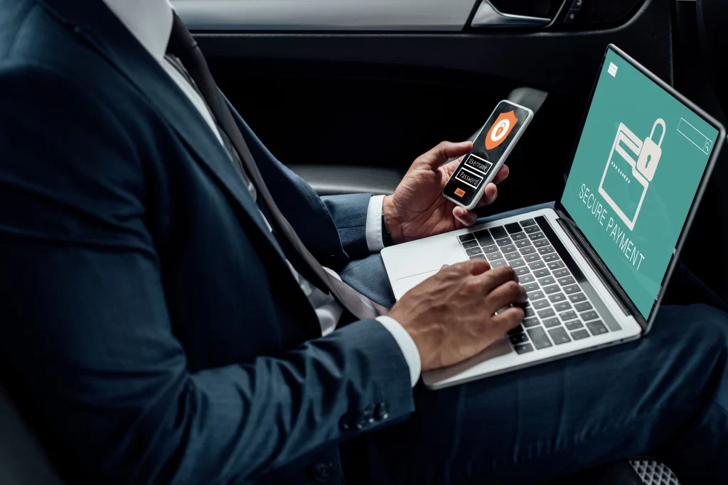 homem com um computador e celular em mãos, representando a cybersegurança