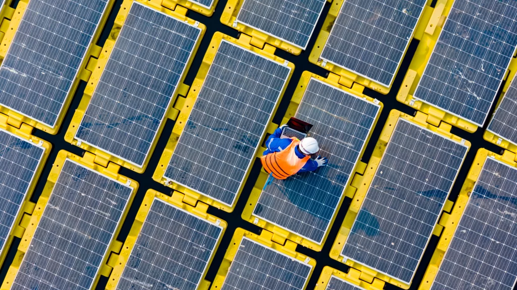 Placas solares e um engenheiro em cima delas.