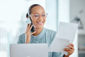 mulher num escritório consultando informações em uma folha de papel